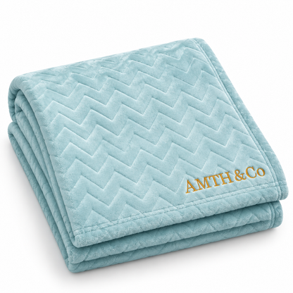 AMTH & Co Haven Blanket folded in light blue with gold wordmark