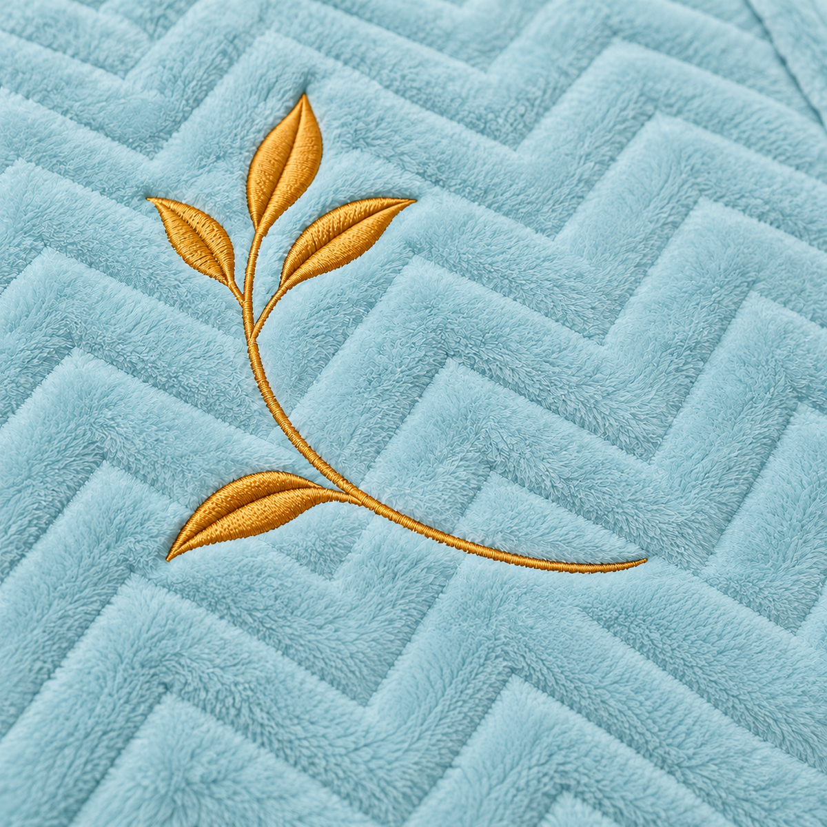 Close-up of the Haven Blanket gold leaf embroidery and chevron texture