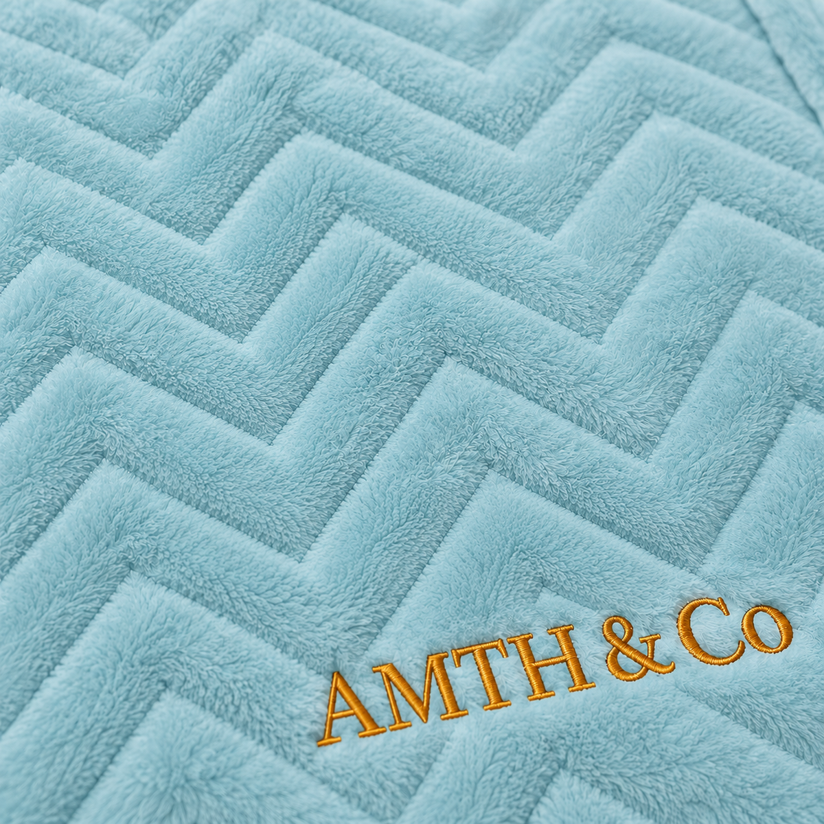 Close-up of the AMTH & Co gold wordmark embroidery on the Haven Blanket