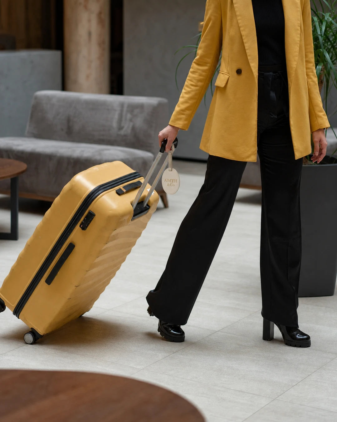 Traveler arriving at a hotel with an AMTH & Co luggage tag
